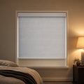 Custom blackout roller blind in Novo Light Grey with a white cassette, shown in a bedroom at dusk