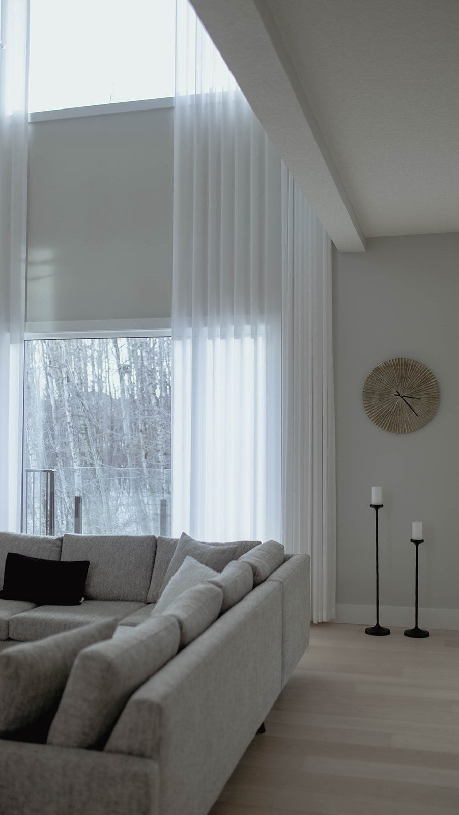 Light roller shades beside a sofa in a tall-window living room.