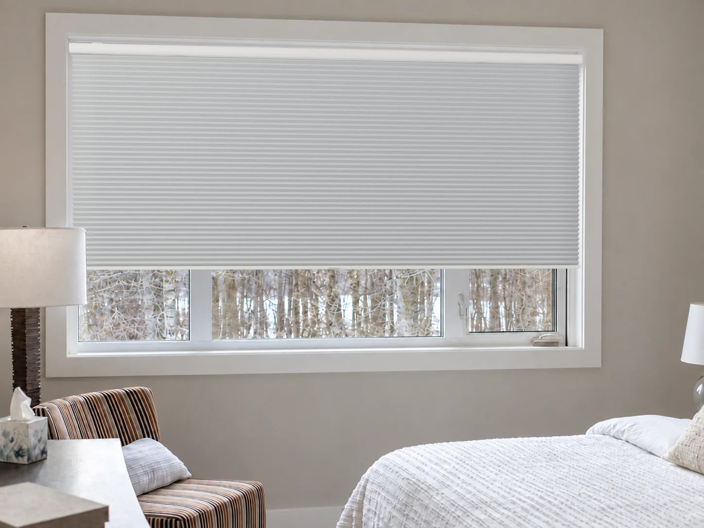 Illustrative bedroom view of a custom cordless honeycomb shade in Classic White BO with a white headrail.